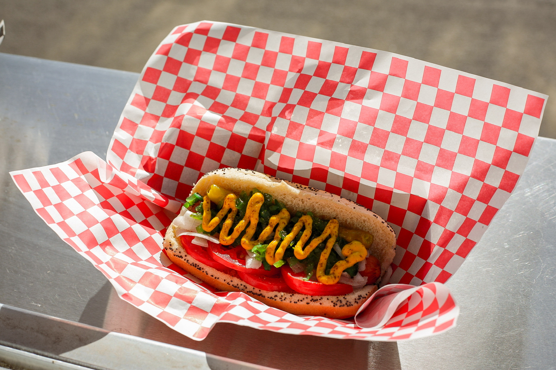 Chicago-style hot dog with mustard, relish, tomato, pickle, and sport peppers