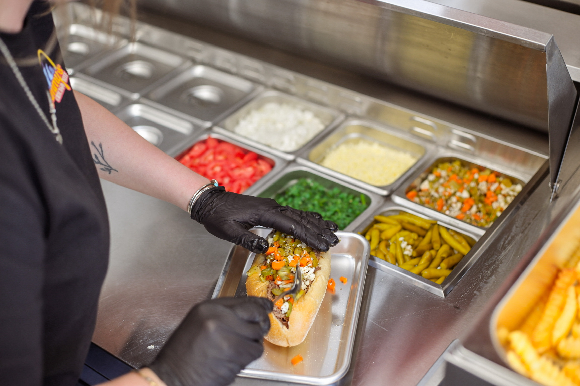 Assembling a Chicago dog with fresh toppings from the prep line