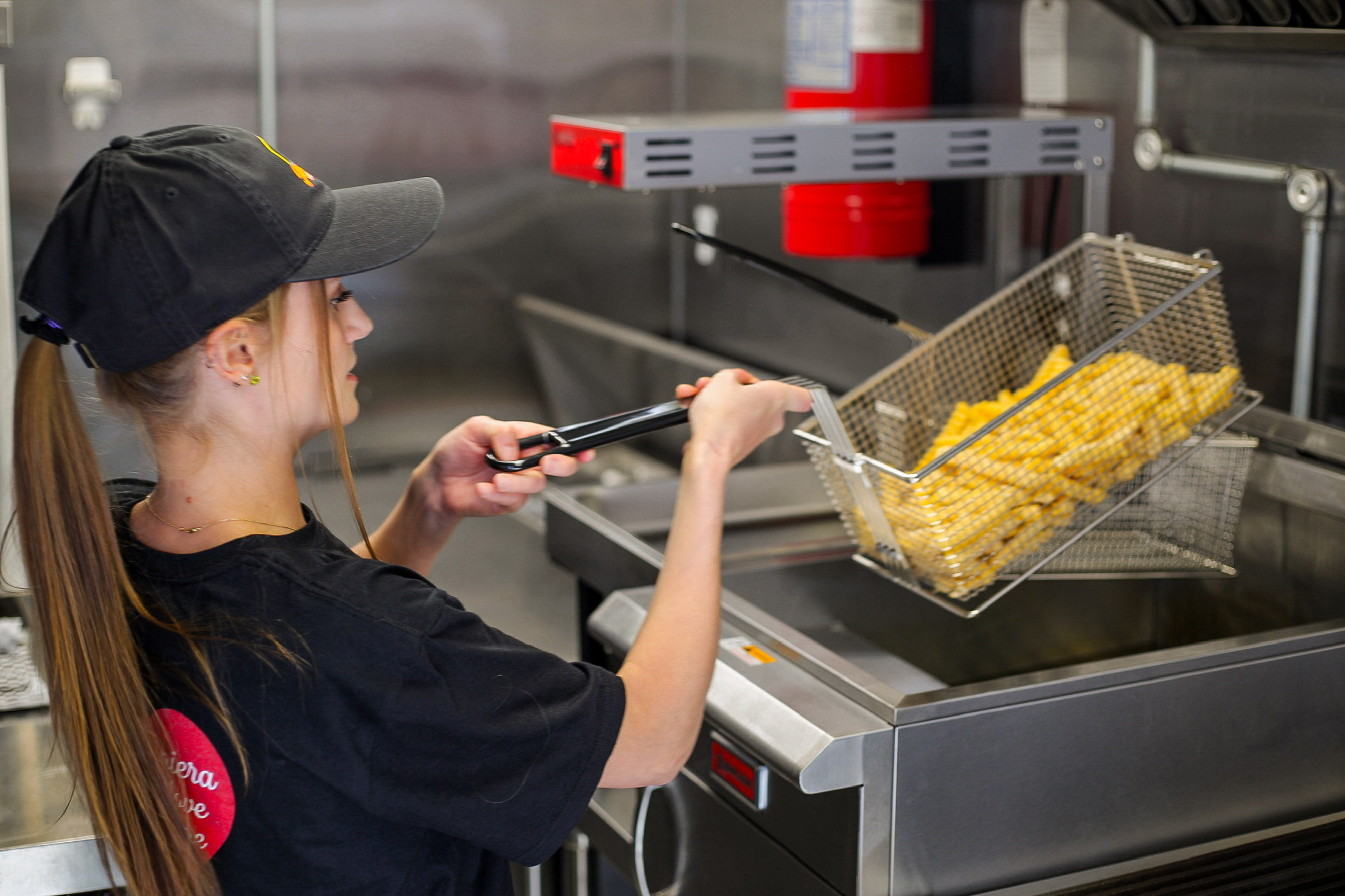Team member lifting a basket of hot fries from the fryer